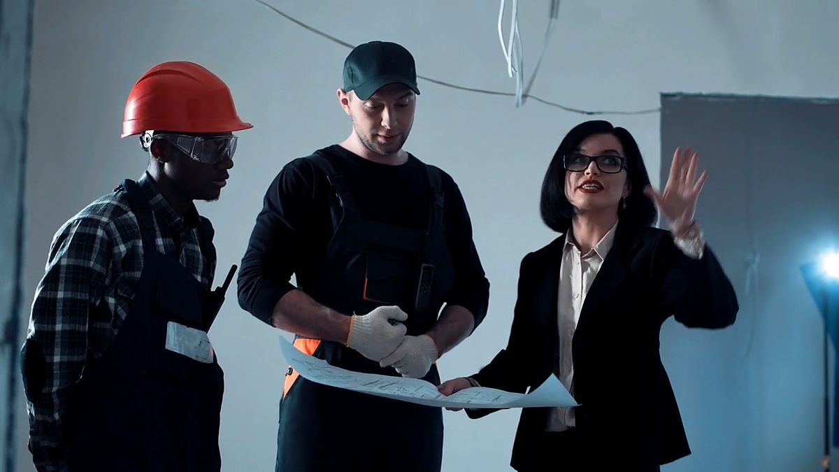 Trois personnes examinent un plan de construction sur un chantier